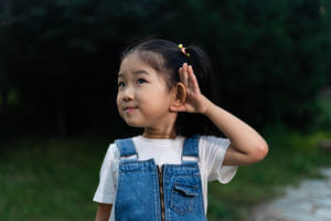 girl with hand to her ear listening